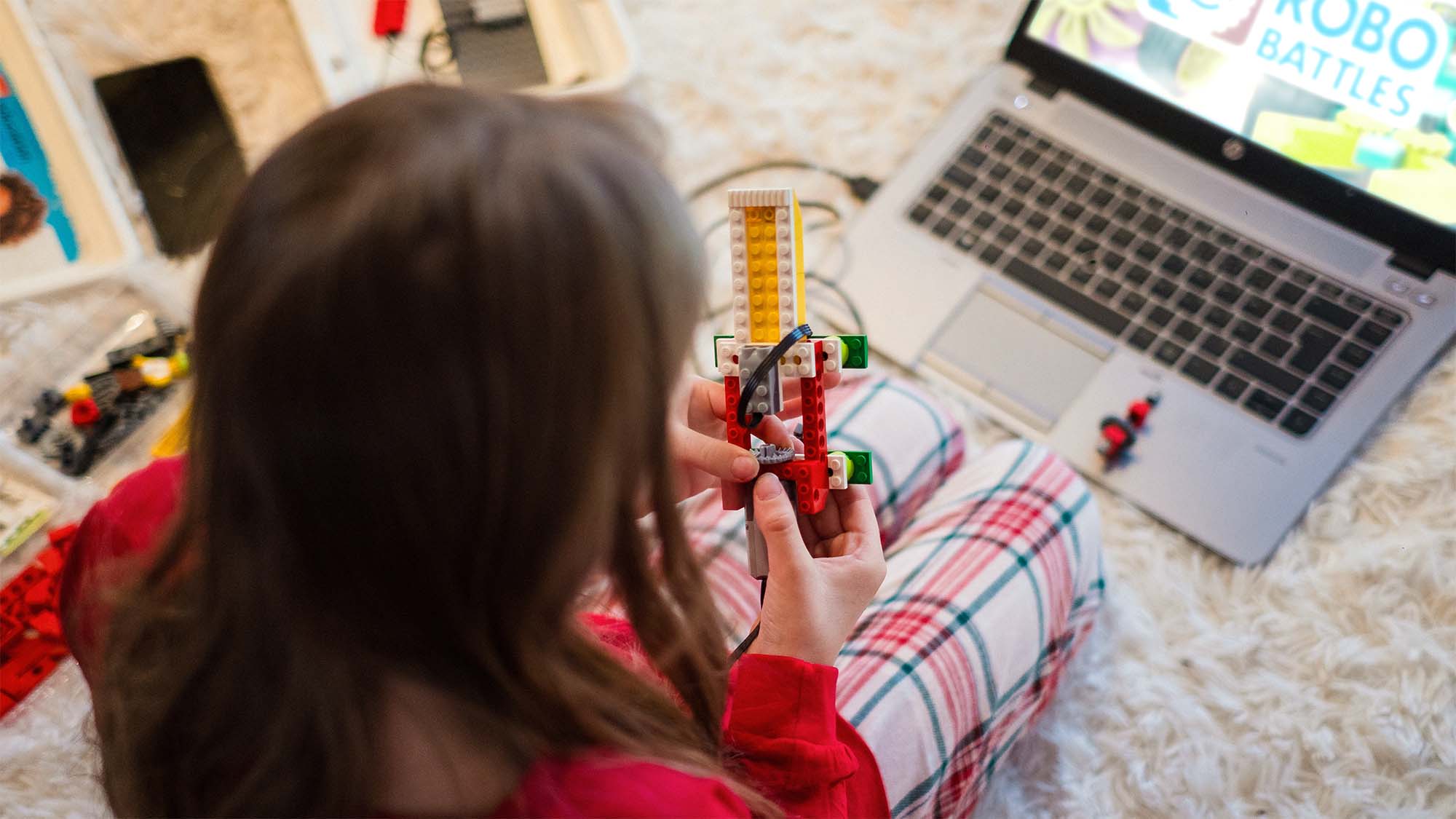 Student building a LEGO mechanism beside a laptop